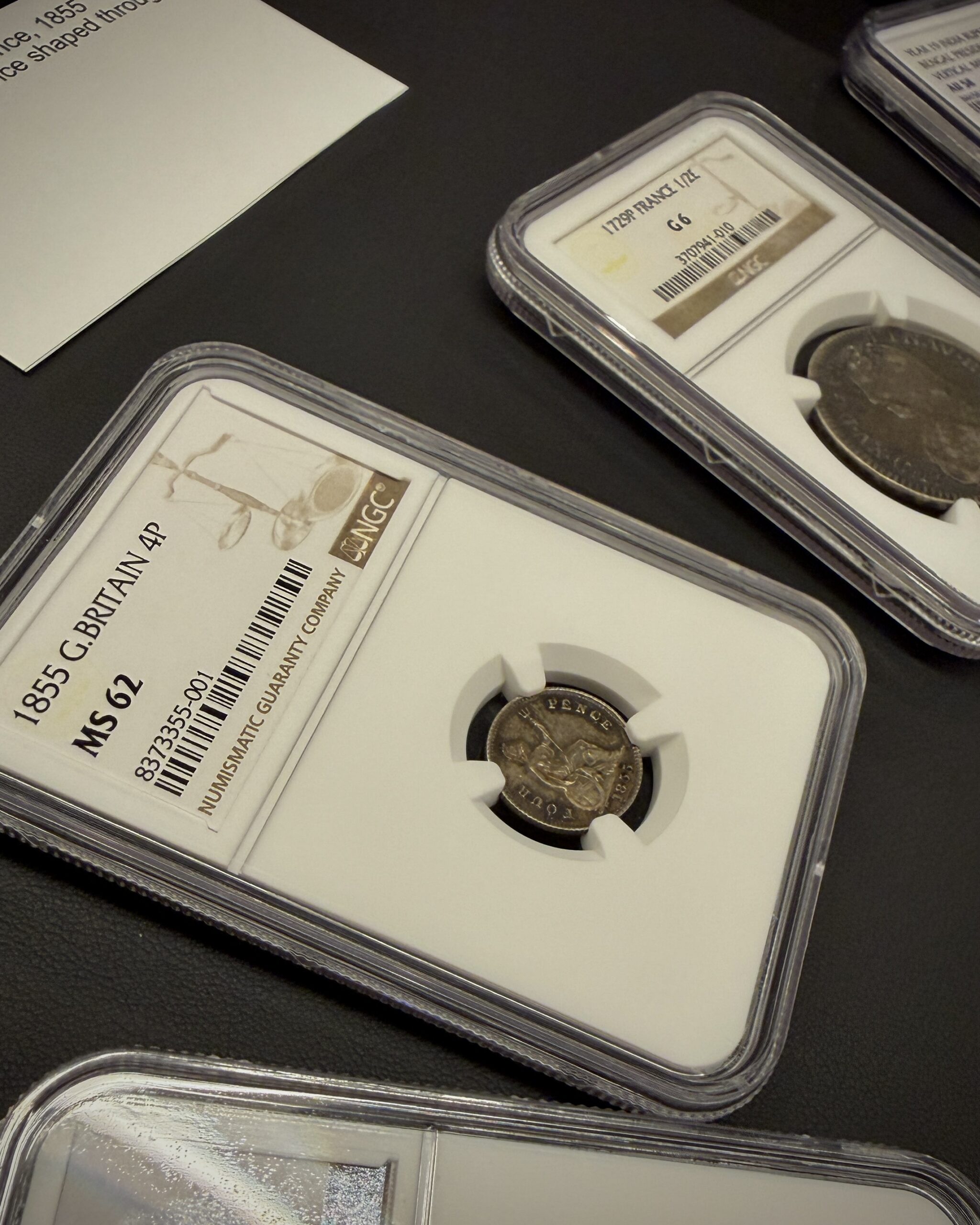 1855 Great Britain Four Pence MS62 displayed alongside a Roman bronze coin and a French 1/2 Ecu during a private viewing by FALJU COINS in Tokyo.